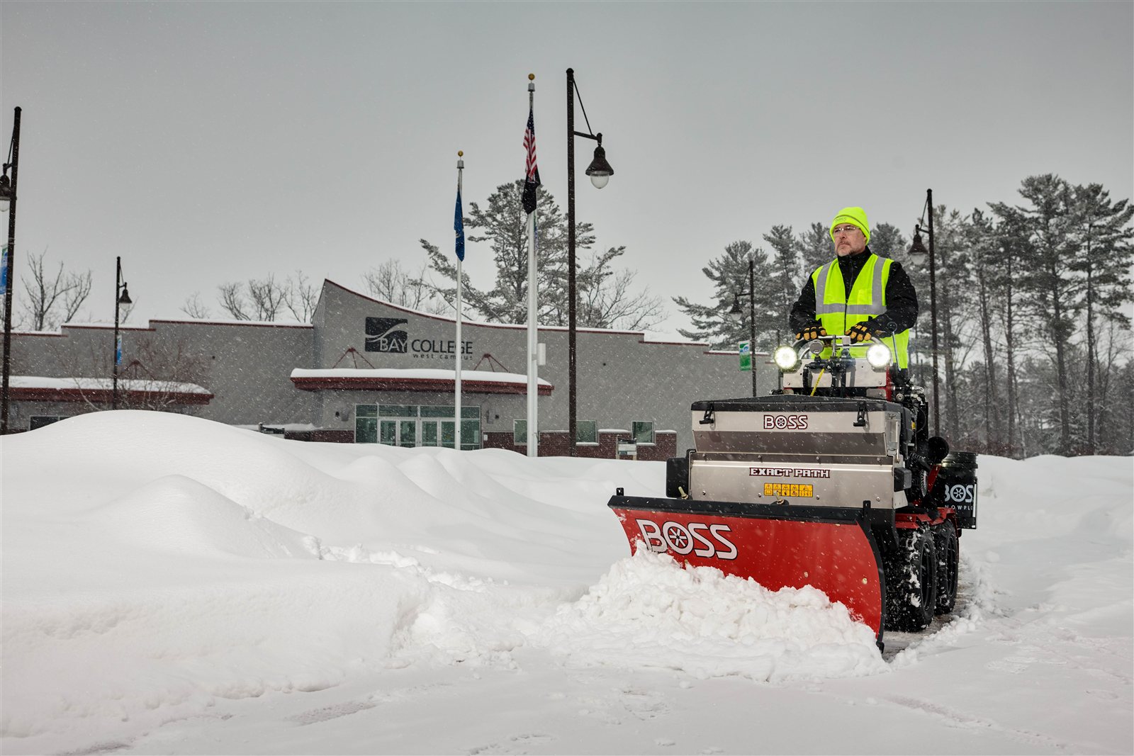 BOSS Snowrator clearing a snowy sidewalk with a straight blade and optional EXACT PATH drop spreader